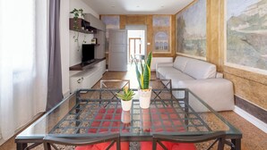 A modern living room with a glass coffee table, a sofa, and a TV on a built-in shelf. - Casa Picta (Bologna)