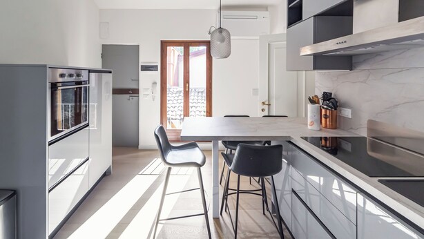 A modern kitchen with a large island, bar stools, and built-in appliances. - Casa Picta (Bologna)