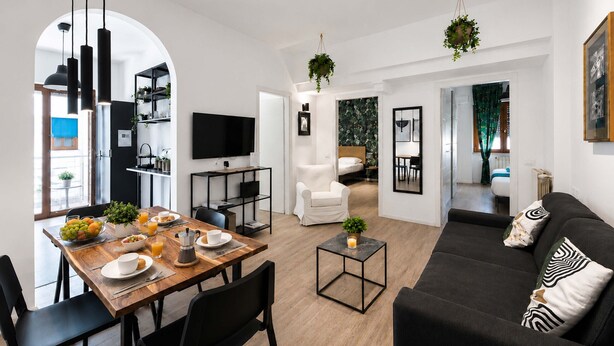 Ett modernt vardagsrum med matplats, soffa, TV och kök.