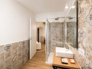 Un baño con ducha, lavamanos y espejo.