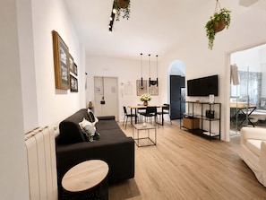 Una sala de estar moderna con sofá, mesa de comedor y televisor.