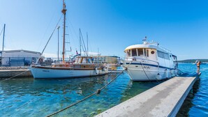 Twee boten aanmeren in een jachthaven met helderblauw water en een betonnen steiger.