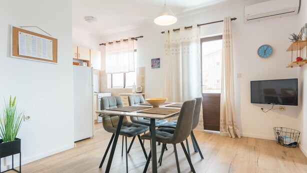 A modern kitchen with a dining area, a TV, and a plant. - Apartment Krešo with Balcony (Biograd na Moru)