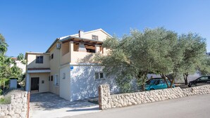 A two-story building with a stone wall and a tree in front. - Apartment Krešo with Balcony (Biograd na Moru)