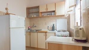 A compact kitchen with a refrigerator, a stove, a sink, and wooden cabinets. - Apartment Krešo with Balcony (Biograd na Moru)