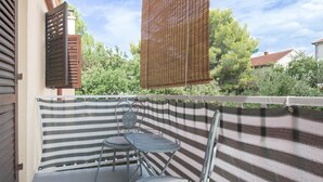 A balcony with a striped fabric barrier, two metal chairs, and a small table. - Apartment Krešo with Balcony (Biograd na Moru)