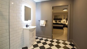 Une salle de bain moderne avec des carreaux de céramique blancs rectangulaires, un lavabo blanc et un sol à carreaux noirs et blancs.