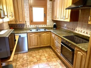 A kitchen with wooden cabinets, a built-in dishwasher, a stove, and a microwave.
