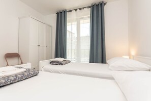 Une chambre avec deux lits, une armoire et une fenêtre avec des rideaux.