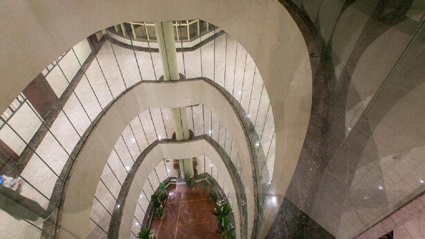 A multi-level interior with a central open space surrounded by curved walls and railings. - The S Hotel (Jeddah)