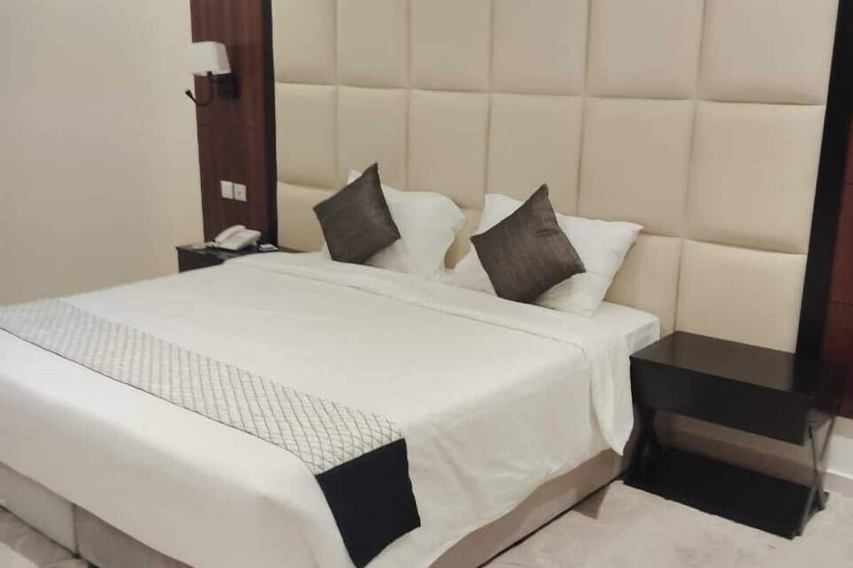 A bedroom with a large bed, a headboard, a bedside table, and a nightstand.