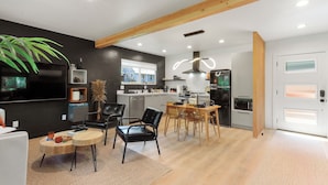 Une cuisine moderne avec des armoires blanches, un réfrigérateur noir et un plafond en bois.