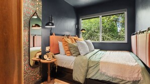 Une chambre à coucher avec un lit, une fenêtre, un miroir et une table de chevet.