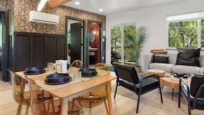 Un salon moderne avec un coin repas, comprenant un canapé, des fauteuils, une table basse et une table à manger avec des assiettes et des verres.