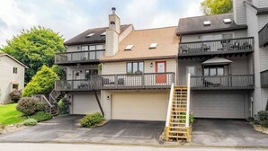 Ein zweistöckiges Wohngebäude mit Garage, einer Holztreppe und einem Balkon.