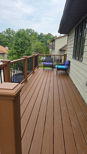 Une terrasse en bois avec une rambarde, un banc et une vue sur un quartier résidentiel.