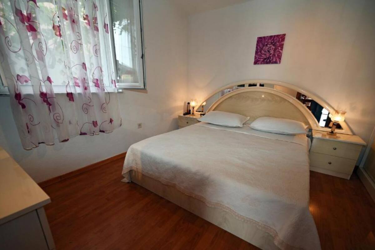 A bedroom with a bed, nightstands, and a window with curtains.