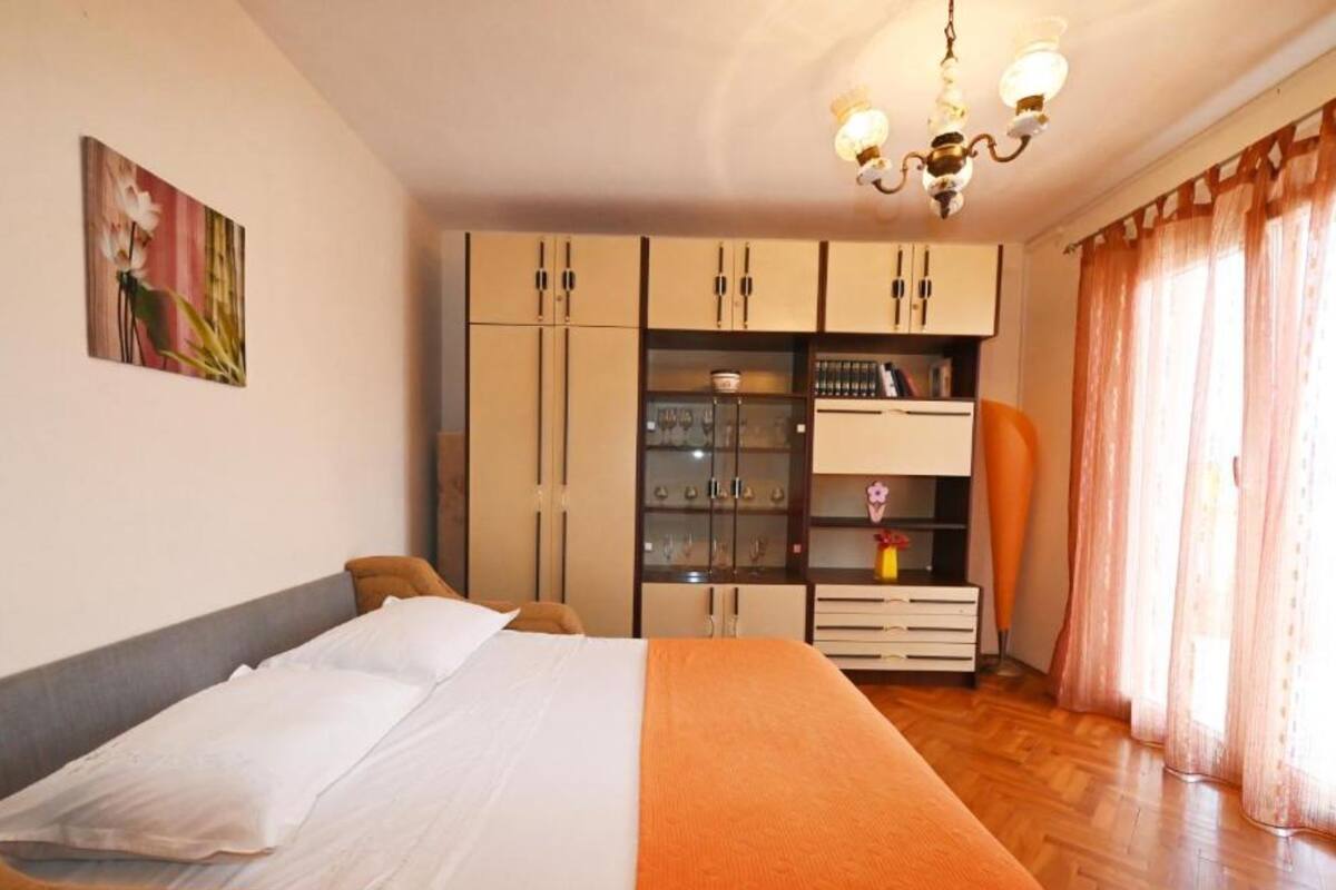 A bedroom with a bed, wardrobe, and a chandelier.