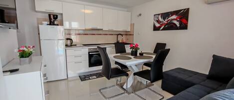 A compact living space with a kitchenette, dining area, and a sofa.