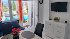 Une chambre moderne équipée d’un canapé, d’une table à manger, d’un téléviseur et offrant une vue sur une piscine.