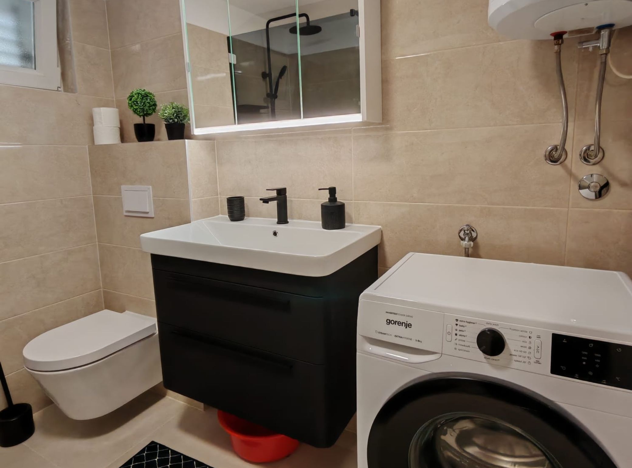 A bathroom with a toilet, sink, mirror, and washing machine.
