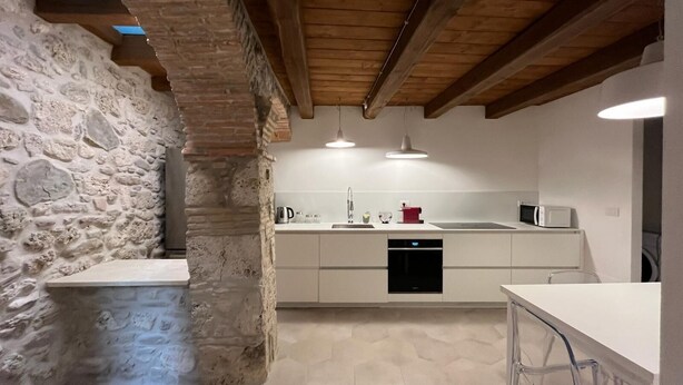 Una cocina con paredes de piedra, vigas de madera y un diseño moderno.