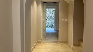 Un pasillo con techo abovedado que conduce a una puerta con vidrio esmerilado.