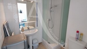 Et badeværelse med vask, spejl, bruser og toilet.