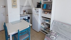 Et kompakt køkken med et hvidt køleskab, en vask og et spisebord med stole.
