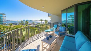 Un balcón con vistas al mar, una piscina y un edificio moderno.