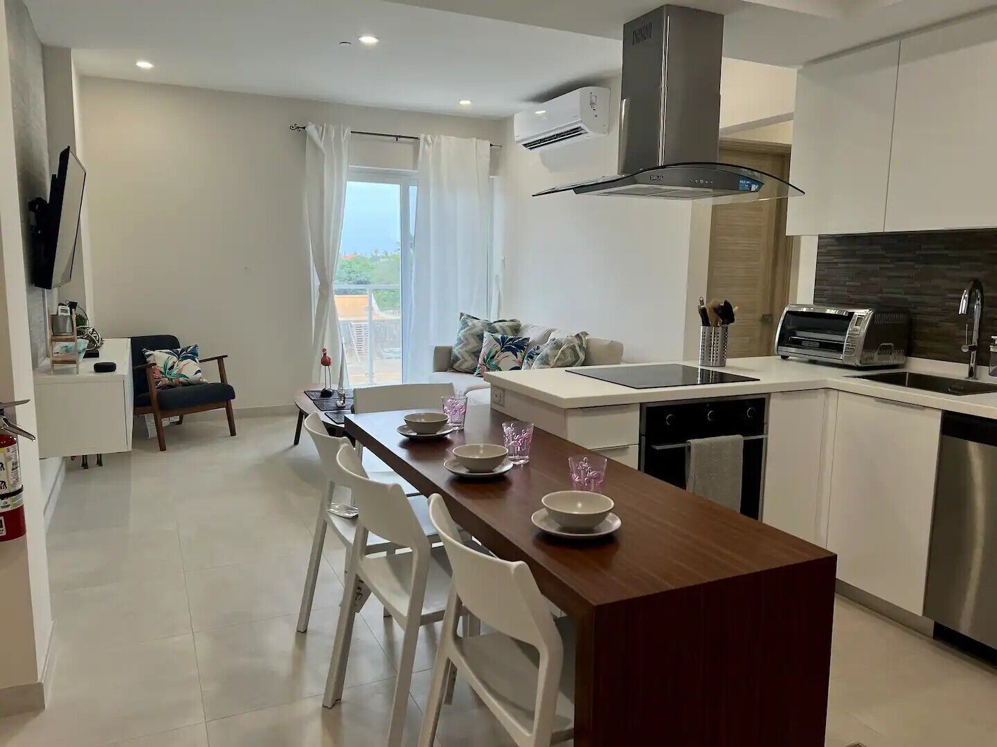 Uma cozinha moderna com ilha central, armários brancos e coifa de aço inoxidável.