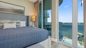 A hotel room with a large bed, a balcony with a view of the water, and a chair outside. - Mustique 802- Luxury Condo with Direct Gulf View a (Gulf Shores)