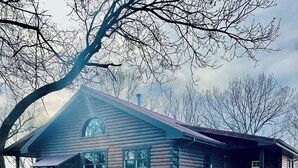 A log cabin with a porch, a bench, and a wagon wheel.