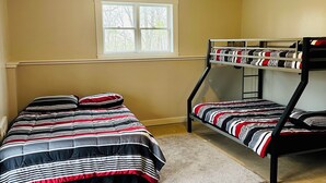 A bedroom with two bunk beds, a window, and a light fixture.