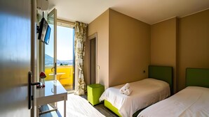 A hotel room with two beds, a desk with a chair, a television, and a window with a view. - Montebello Lake (Lecco)