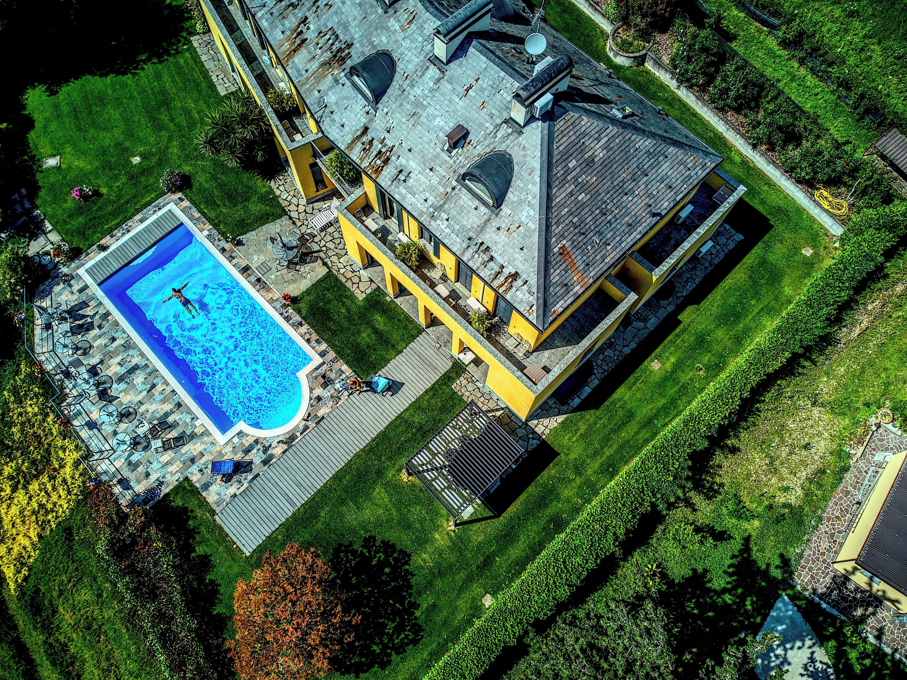An aerial view of a house with a swimming pool, a well-maintained lawn, and a satellite dish.