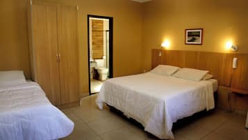 Een hotelkamer met een bed, een kledingkast, een badkamer en een nachtkastje met een lamp.