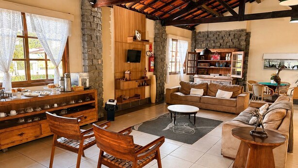 Una sala de estar amplia con pared de piedra, muebles de madera, chimenea y televisor.