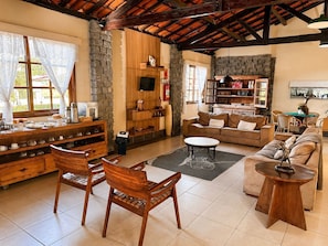 A spacious living room with a stone wall, wooden furniture, a fireplace, and a television.