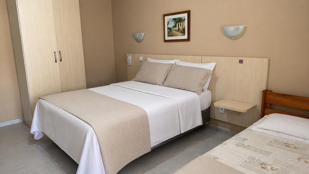 Ein Schlafzimmer mit Bett, Nachttisch, Kleiderschrank und einer Wandleuchte.