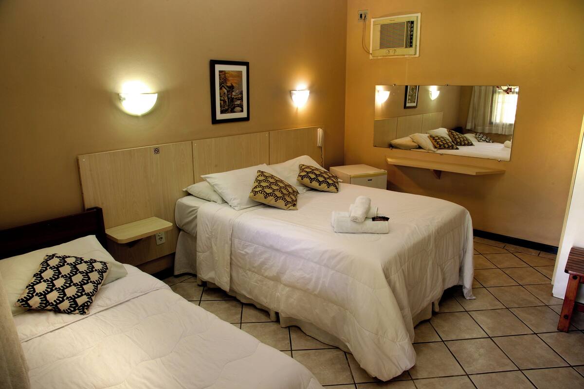 Ein Hotelzimmer mit zwei Betten, einem Nachttisch, einem Wandspiegel und einer Wandleuchte.