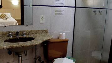 Casa de banho com lavatório, sanita e cabine de duche em vidro.