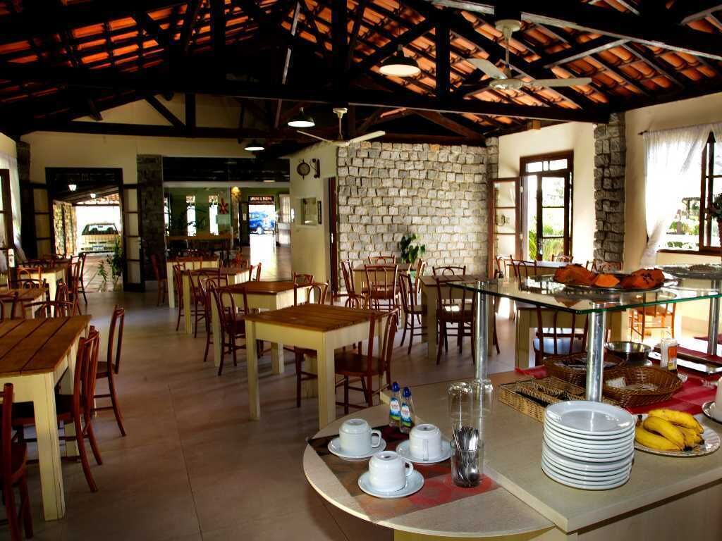 Un comedor con mesas y sillas de madera, una pared de piedra y un mostrador de buffet con platos y plátanos.