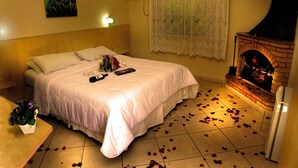 Un dormitorio con cama, chimenea y pétalos de rosa en el suelo.