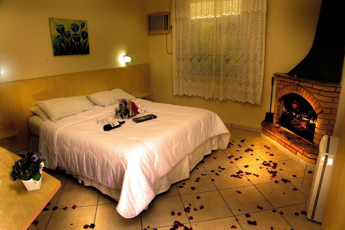 Ein Schlafzimmer mit Bett, Kamin und Rosenblüten auf dem Boden.