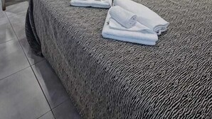Quarto de hotel com cama grande, mesa de cabeceira, cadeira, escrivaninha e espelho.