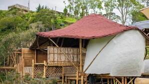 Una estructura de bambú con una cúpula cubierta de tela blanca y un techo rojo.