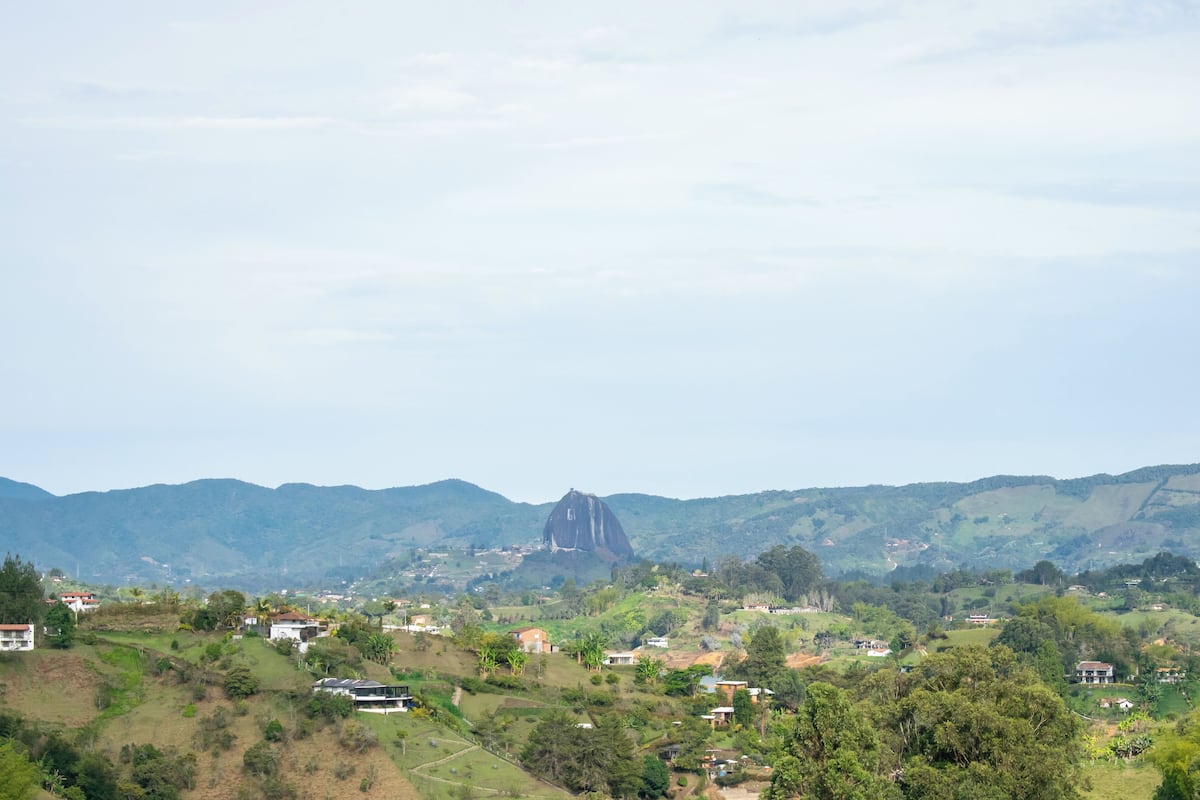 A rural landscape with scattered houses, a prominent mountain, and a clear sky.