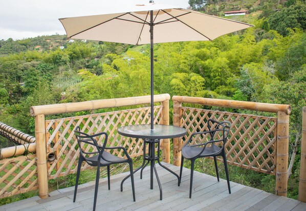 A bamboo deck with a glass table and two chairs, surrounded by a wooden lattice fence.