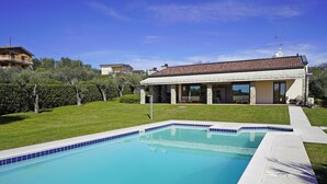 A residential property with a swimming pool, a covered patio, and a view of neighboring houses.